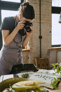 Food-Stylist fotografiert mit Digitalkamera bei der Arbeit im Studio - MASF33929