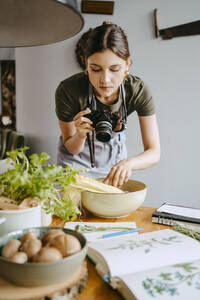 Food-Stylist fotografiert Gemüseschale mit Digitalkamera im Studio - MASF33931