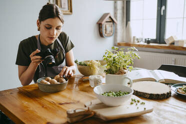 Food-Stylist fotografiert Pilze durch eine Digitalkamera im Studio - MASF33933