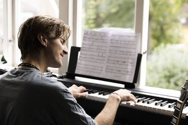 Passionate young man playing piano at home - MASF33981