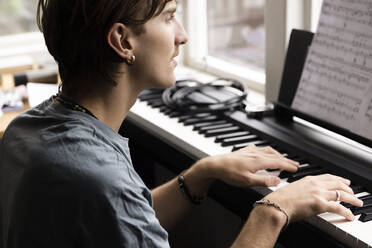 Concentrated young man practicing piano at home - MASF33982