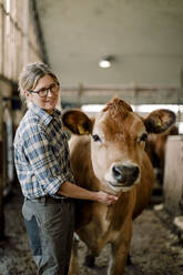 Glücklicher reifer Bauer mit Kuh auf einer Rinderfarm - MASF34024