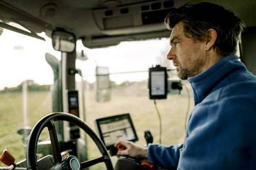 Älterer Landwirt fährt Traktor auf einem Feld - MASF34027