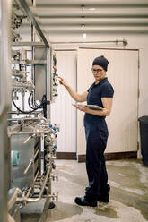 Farmer using digital tablet PC and operating machine at dairy factory - MASF34050