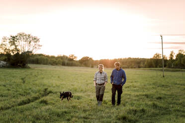 Älteres Paar mit Hund beim Spaziergang auf einem Feld bei Sonnenuntergang - MASF34073