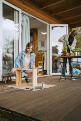 Junge Frau baut Möbel mit Mann bei der Gartenarbeit auf der Veranda - MASF34118