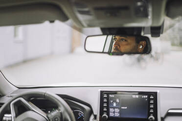 Reflexion eines männlichen Pendlers im Rückspiegel eines Autos - MASF34155