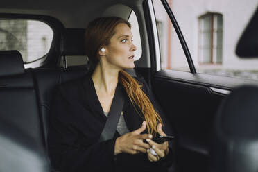 Businesswoman with brown hair sitting in car - MASF34160