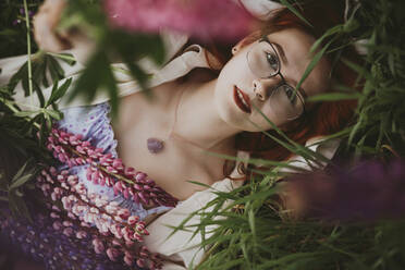 Teenager-Mädchen auf Gras mit Lupinenblüten liegend - IEF00266