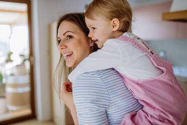 Eine junge Mutter, die ihre kleine Tochter huckepack nimmt. - HPIF03235