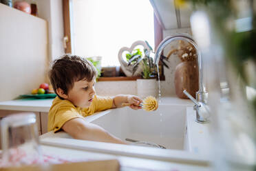 Ein kleiner Junge wäscht Tasse in der Spüle in der Küche mit hölzernen schrubben, nachhaltige lifestlye. - HPIF03251