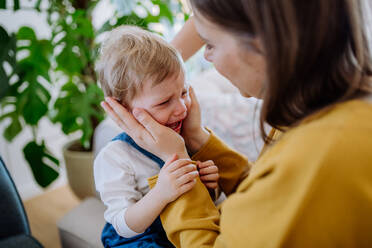 Eine Mutter tröstet ihre kleine verstörte Tochter zu Hause. - HPIF03258