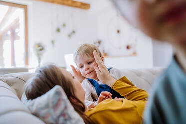 Eine junge, fröhliche Mutter spielt mit ihren kleinen Kindern und hat Spaß im Wohnzimmer. - HPIF03271