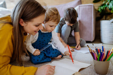 Eine Mutter mit ihren kleinen Kindern, die zu Hause gemeinsam malen. - HPIF03278