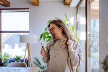 A happy young woman with earphones dancing, enjoying leisure weekend at home, stress free concept - HPIF03299