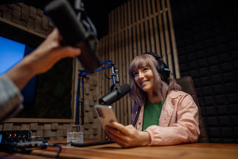 Eine junge Moderatorin spricht in ein Mikrofon und interviewt einen Mann für einen Radio-Podcast. - HPIF03339