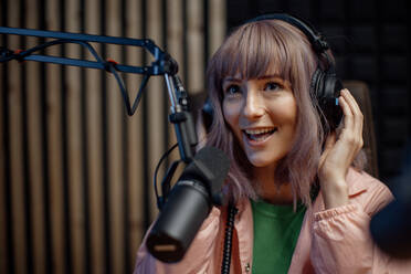 A portrait of female radio host speaking in microphone while moderating a live show - HPIF03341