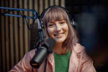 A portrait of female radio host speaking in microphone while moderating a live show - HPIF03342