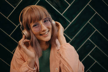 A young woman wearing headphones and enjoying listening to music indoors. - HPIF03344