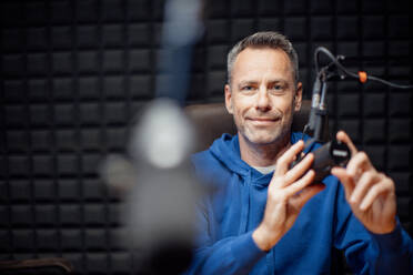 Ein Porträt eines reifen Radiomoderators, der in ein Mikrofon spricht, während er eine Live-Sendung moderiert - HPIF03353