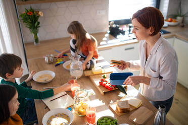 Eine Mutter von drei kleinen Kindern bereitet das Frühstück in der Küche zu Hause vor. - HPIF03368
