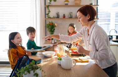 Eine Mutter von drei kleinen Kindern bereitet das Frühstück in der Küche zu Hause vor. - HPIF03370