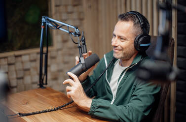 Ein Porträt eines reifen Radiomoderators, der in ein Mikrofon spricht, während er eine Live-Sendung moderiert - HPIF03391