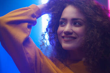 A portrait of a happy young woman dancing over neon light background at disco party - HPIF03395