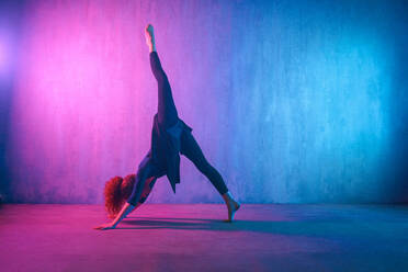 Eine moderne Tänzerin tanzt im Neonlicht und macht Gymnastikübungen im Studio, Kopierraum. - HPIF03409