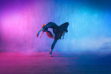 Eine moderne Tänzerin tanzt im Neonlicht und macht Gymnastikübungen im Studio, Kopierraum. - HPIF03411