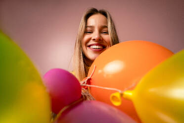 Ein Studio-Porträt eines glücklichen jungen blonde Frau mit Luftballons über rosa Hintergrund. - HPIF03432