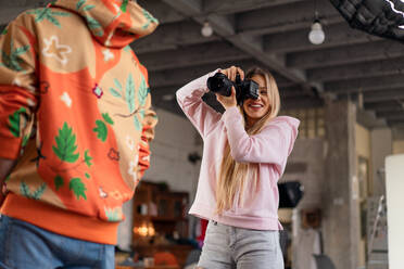 Eine junge Fotografin macht Fotos von einem Modell, hinter der Bühne eines Fotoshootings im Studio. - HPIF03452