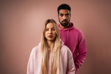 Ein Mode-Studio Porträt eines glücklichen jungen blonde Frau in Hoodie posiert über rosa Hintergrund. - HPIF03458