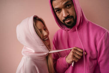 Ein Mode-Studio Porträt eines glücklichen jungen blonde Frau in Hoodie posiert über rosa Hintergrund. - HPIF03461