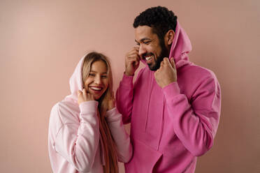 Ein Mode-Studio Porträt eines glücklichen jungen blonde Frau in Hoodie posiert über rosa Hintergrund. - HPIF03462