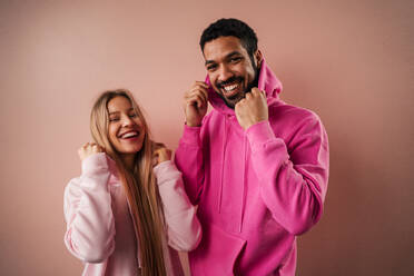 Ein Mode-Studio Porträt eines glücklichen jungen blonde Frau in Hoodie posiert über rosa Hintergrund. - HPIF03463