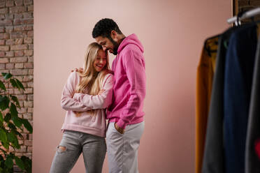 Ein Mode-Studio Porträt eines glücklichen jungen blonde Frau in Hoodie posiert über rosa Hintergrund. - HPIF03464