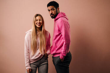 Ein Mode-Studio Porträt eines glücklichen jungen blonde Frau in Hoodie posiert über rosa Hintergrund. - HPIF03467