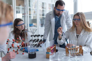 Science students with a teacher doing chemical reaction experiment in the laboratory at university. - HPIF03482