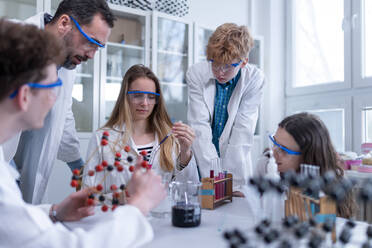 Studenten der Naturwissenschaften mit einem Lehrer bei einem chemischen Reaktionsexperiment im Labor an der Universität. - HPIF03483