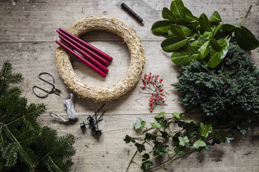 Preparation of Christmas wreath made of spruce, juniper, ivy, rose hips and candles - EVGF04187