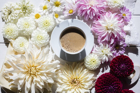 Tasse Kaffee, umgeben von Köpfen verschiedener blühender Blumen - EVGF04210