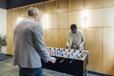 Multirassische Geschäftsleute spielen Tischfußball im Büro - VPIF07706