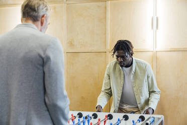 Young businessman with colleague playing foosball in office - VPIF07707