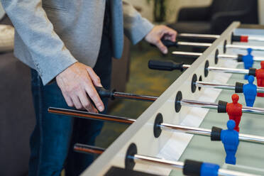 Hands of businessman playing foosball in office - VPIF07709