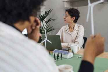 Businesswoman with colleague sitting at table in office - VPIF07757