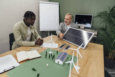 Geschäftsleute diskutieren an einem Tisch im Büro über ein Solarpanel - VPIF07774