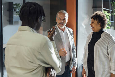 Businessman discussing with colleagues standing in corridor - VPIF07780