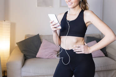 Young woman with headphones using smart phone at home - JPTF01206