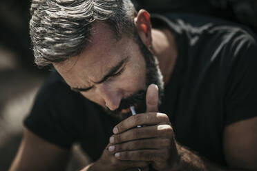 Mature man with beard igniting cigarette - MJRF00796